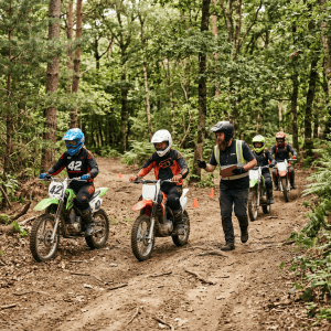 Four dirt bike riders with helmets riding on a forest trail guided by an instructor